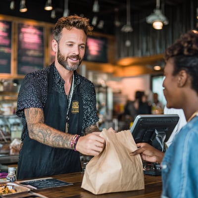 popcorngtm_a_male_fast_casual_restaurant_worker_handing_a_tak_0f98a4a3-a8cf-4dc2-b6b0-9901fa7940f9_0